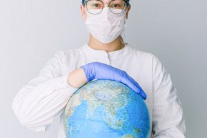 person with a face mask and latex gloves holding a globe